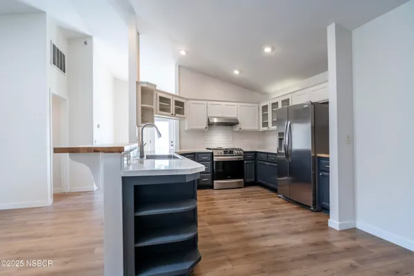 a kitchen with stainless steel appliances granite countertop a sink refrigerator and cabinets