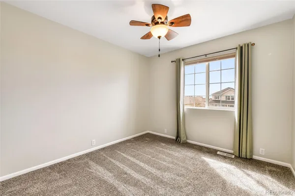 an empty room with a window and a ceiling fan