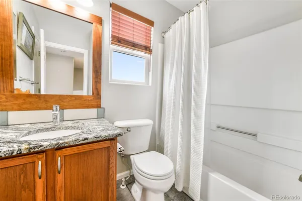 a bathroom with a granite countertop sink toilet and mirror