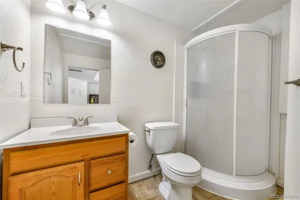 a bathroom with a granite countertop toilet sink and mirror