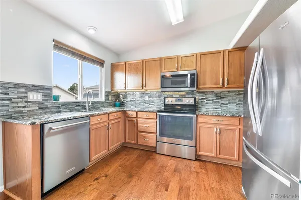 a kitchen with stainless steel appliances granite countertop a refrigerator stove top oven and sink
