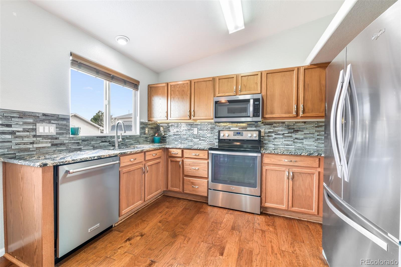 12906 Oakland Hills Road Peyton, CO 80831 - Photo 7 of 50 a kitchen with stainless steel appliances granite countertop a refrigerator stove top oven and sink