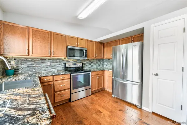 a kitchen with granite countertop wooden cabinets a stove top oven and stainless steel appliances