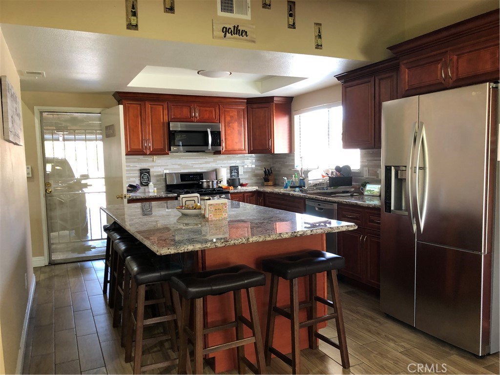 8864 Haskell Street Riverside, CA 92503 - Photo 4 of 18 a kitchen with stainless steel appliances granite countertop a kitchen island a table and chairs in it