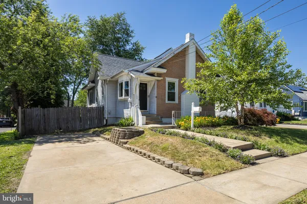 a view of a brick house with a small yard plants and a large tree