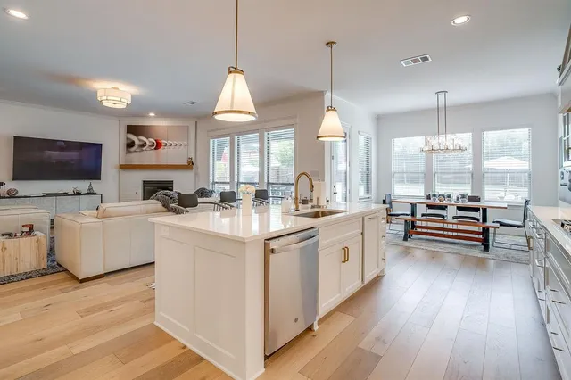 a large kitchen with kitchen island granite countertop a stove a sink dishwasher a dining table and chairs with wooden floor