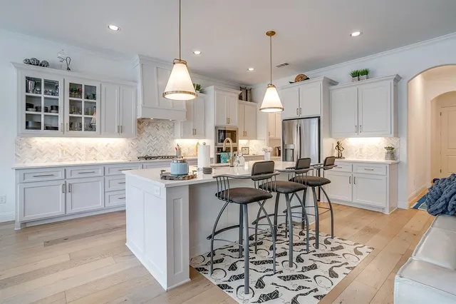 a kitchen with kitchen island a stove a table and chairs in it