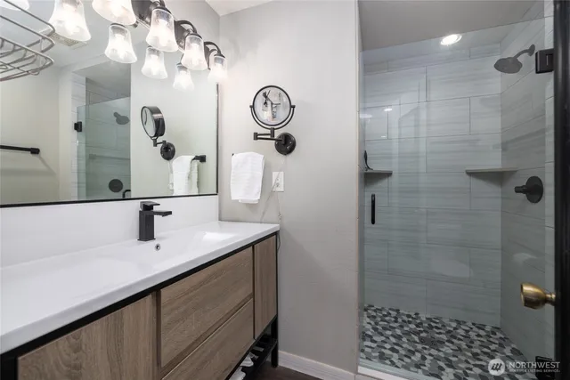 a bathroom with a sink a mirror a vanity and shower