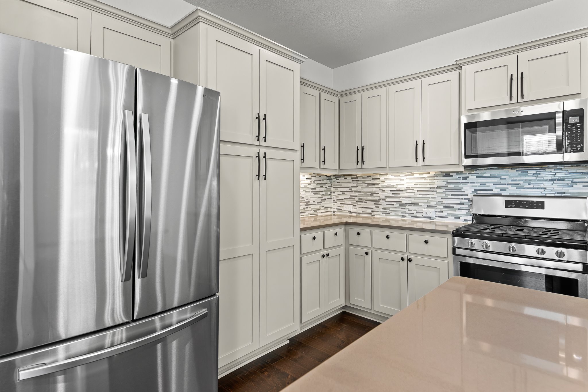 13800 Lyndhurst Street, Unit 211 Austin, TX 78717 - Photo 11 of 40 Kitchen featuring stainless steel appliances, backsplash, light stone countertops, dark wood-style flooring, and white cabinets