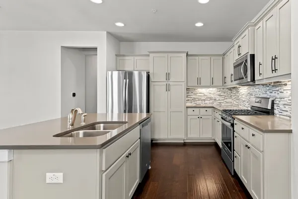 a kitchen with stainless steel appliances granite countertop a sink stove refrigerator and cabinets