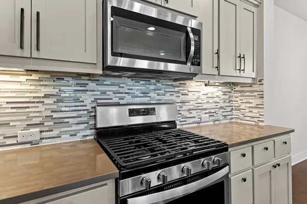 a kitchen with granite countertop a stove top oven microwave and cabinets