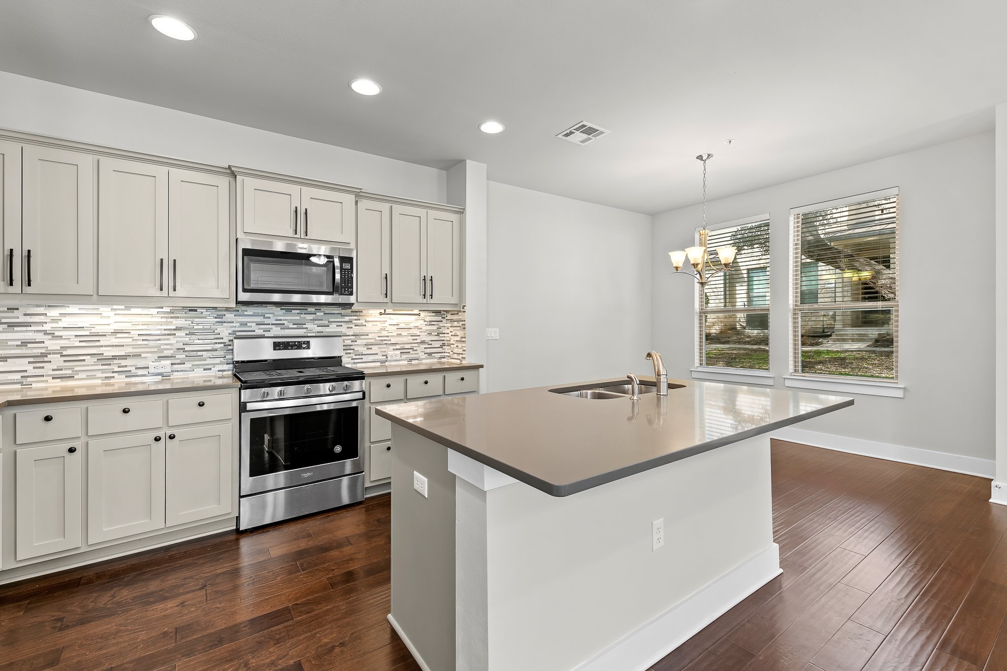 13800 Lyndhurst Street, Unit 211 Austin, TX 78717 - Photo 7 of 40 Kitchen featuring stainless steel appliances, a center island with sink, dark wood-type flooring, and tasteful backsplash