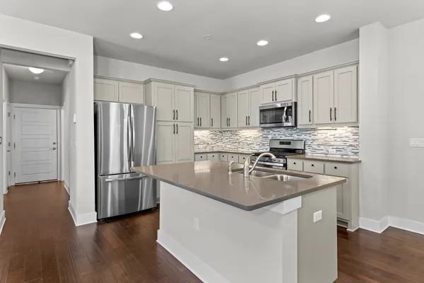 a kitchen with stainless steel appliances granite countertop a refrigerator a stove a sink a microwave and cabinets