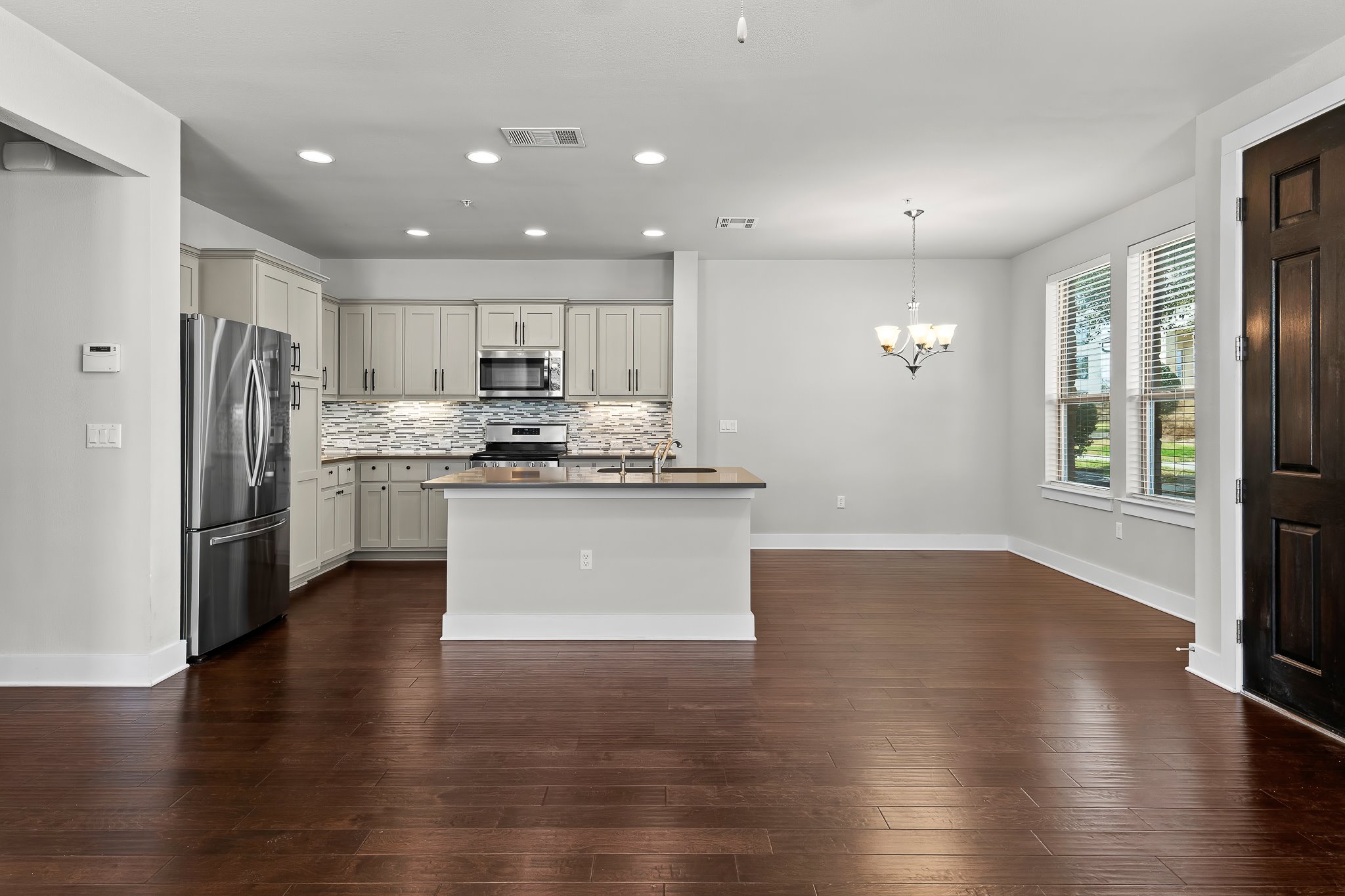 13800 Lyndhurst Street, Unit 211 Austin, TX 78717 - Photo 10 of 40 Kitchen featuring stainless steel appliances, a kitchen island with sink, dark wood-style flooring, a chandelier, and tasteful backsplash