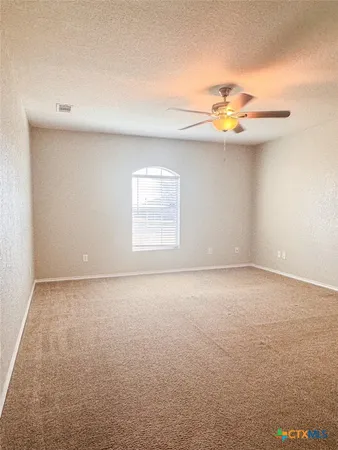 an empty room with windows and chandelier fan