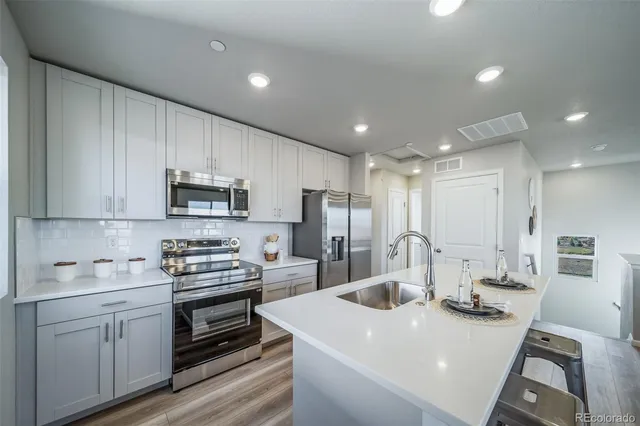 a kitchen with stainless steel appliances a sink a stove a microwave a refrigerator and cabinets