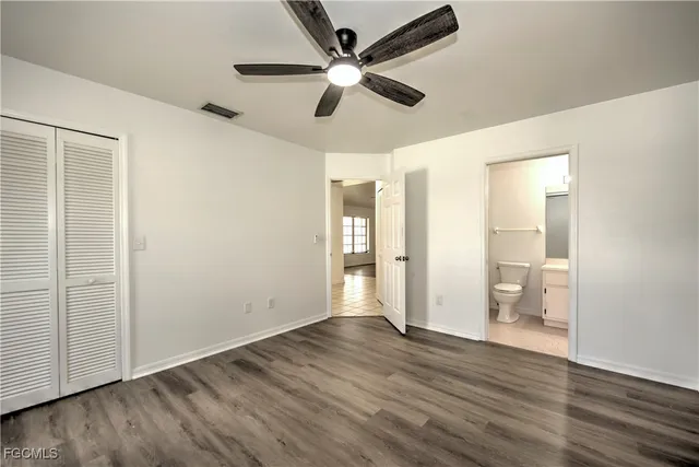 an empty room with wooden floor and a ceiling fan