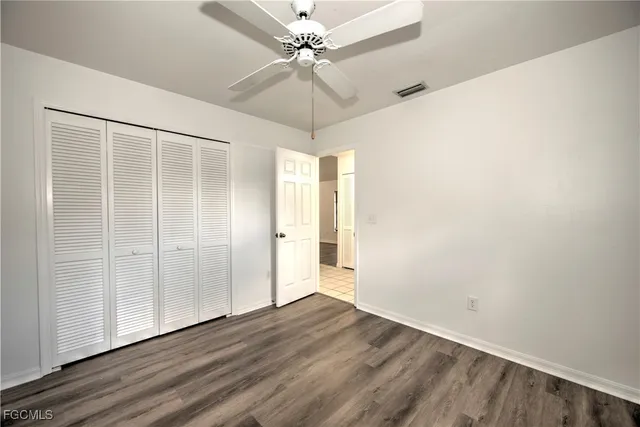 an empty room with wooden floor fan and windows