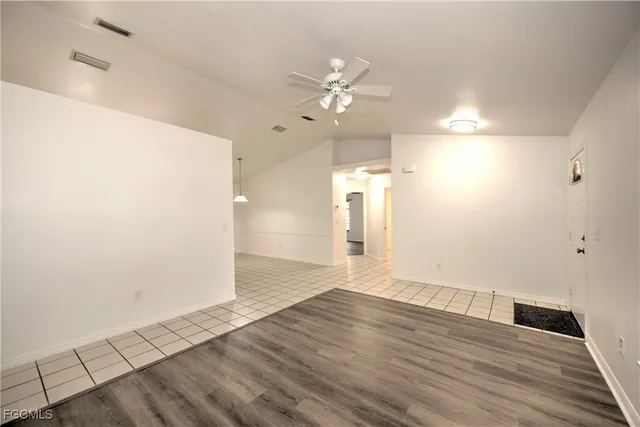 an empty room with wooden floor and ceiling fan