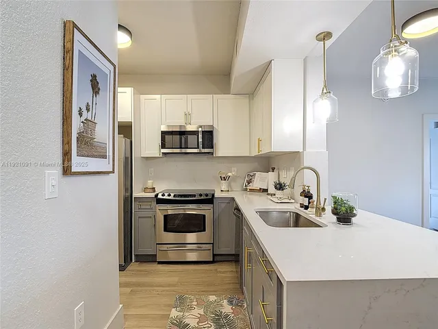 a kitchen with stainless steel appliances a sink a stove a microwave a refrigerator cabinets and living room view