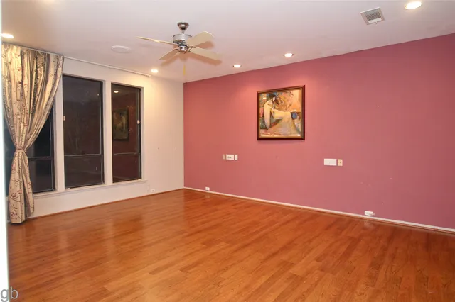 a view of an empty room with window and wooden floor
