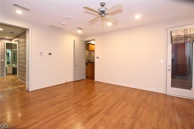 an empty room with wooden floor and a ceiling fan
