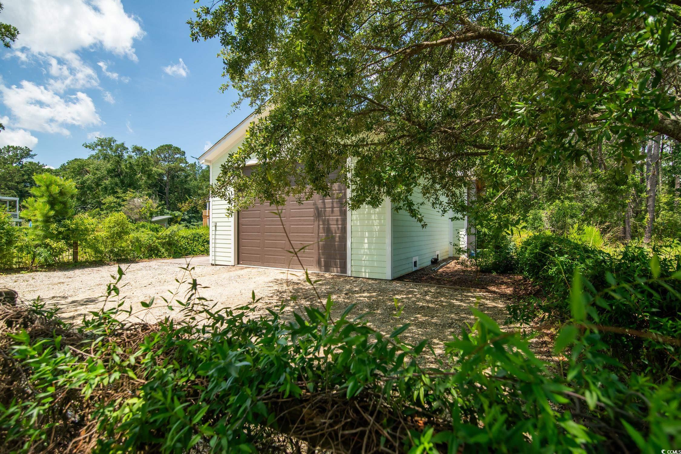 127 Brown Pelican Loop Pawleys Island, SC 29585 - Photo 21 of 31 View of yard with dirt driveway, an outdoor structure, and an attached garage