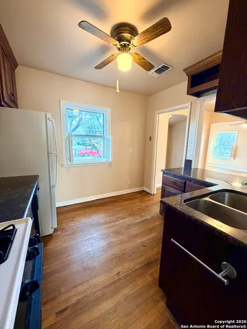 a kitchen with stainless steel appliances granite countertop a sink a stove a refrigerator a microwave oven with wooden floor and cabinets