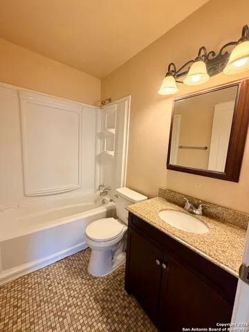 a bathroom with a granite countertop sink toilet and mirror