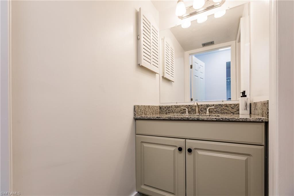 600 Neapolitan Way, Unit 152 Naples, FL 34103 - Photo 12 of 41 a bathroom with a granite countertop sink and a mirror