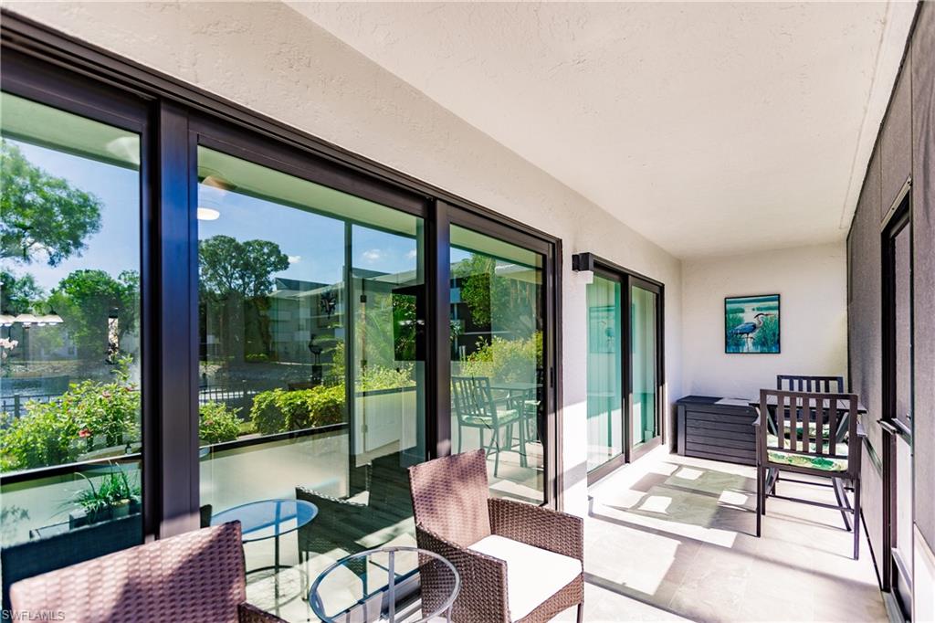 600 Neapolitan Way, Unit 152 Naples, FL 34103 - Photo 17 of 41 a living room with furniture and floor to ceiling windows