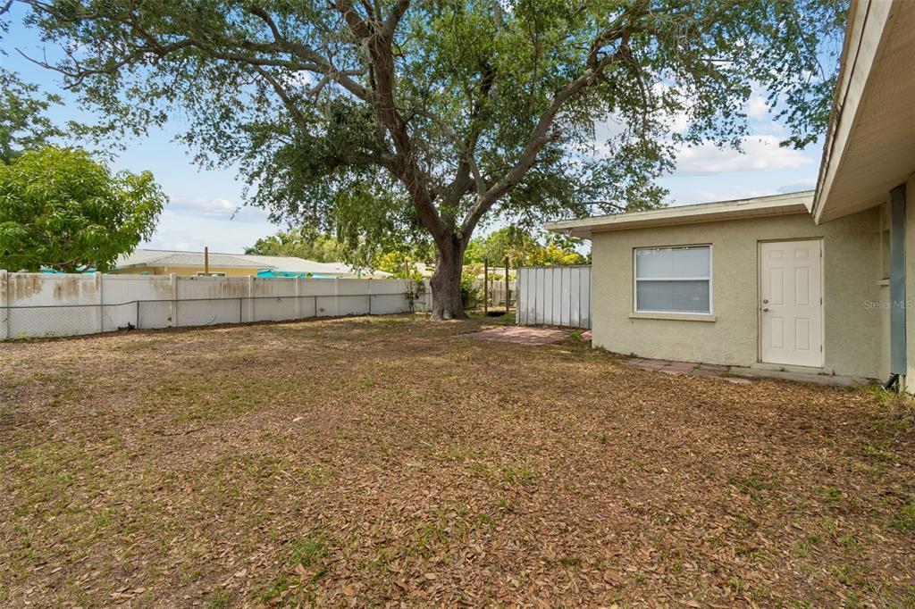 4018 Prado Drive Sarasota, FL 34235 - Photo 64 of 74 a backyard of a house with large trees and brick wall