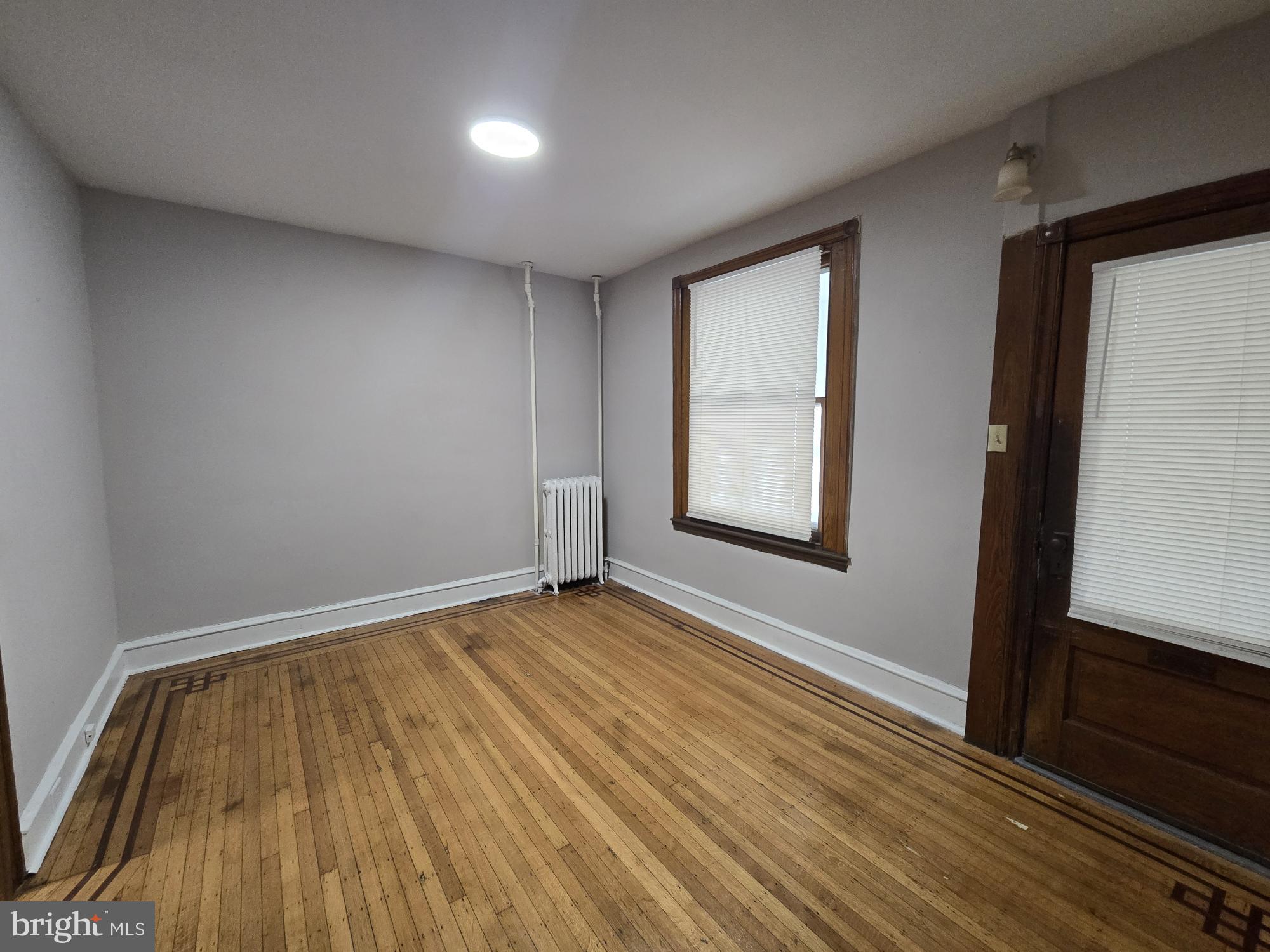 4254 North 7th Street Philadelphia, PA 19140 - Photo 6 of 26 a view of an empty room with wooden floor and a window