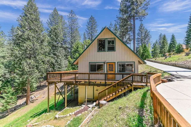 a view of a house with a small yard and wooden deck