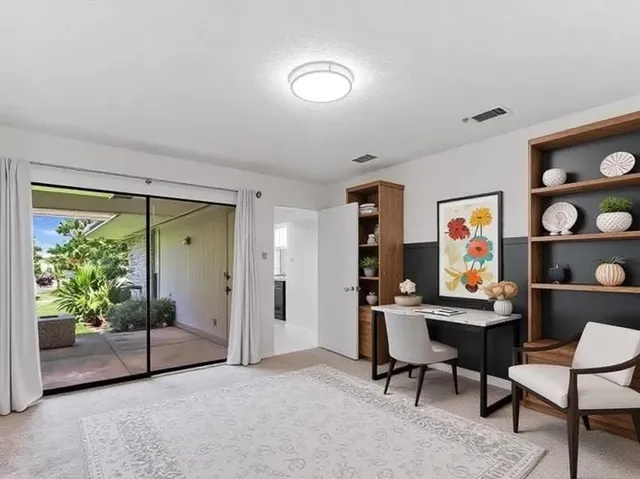 a view of a workspace with furniture and a window