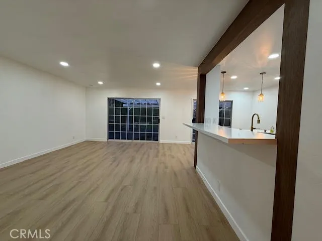 an empty room with wooden floor and kitchen view