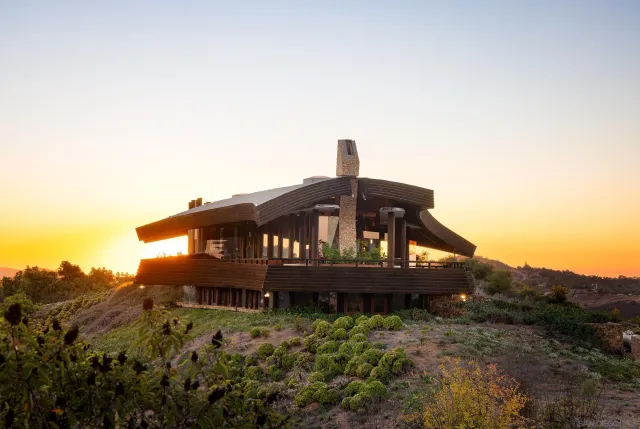 a view of a big house with a small yard and large trees