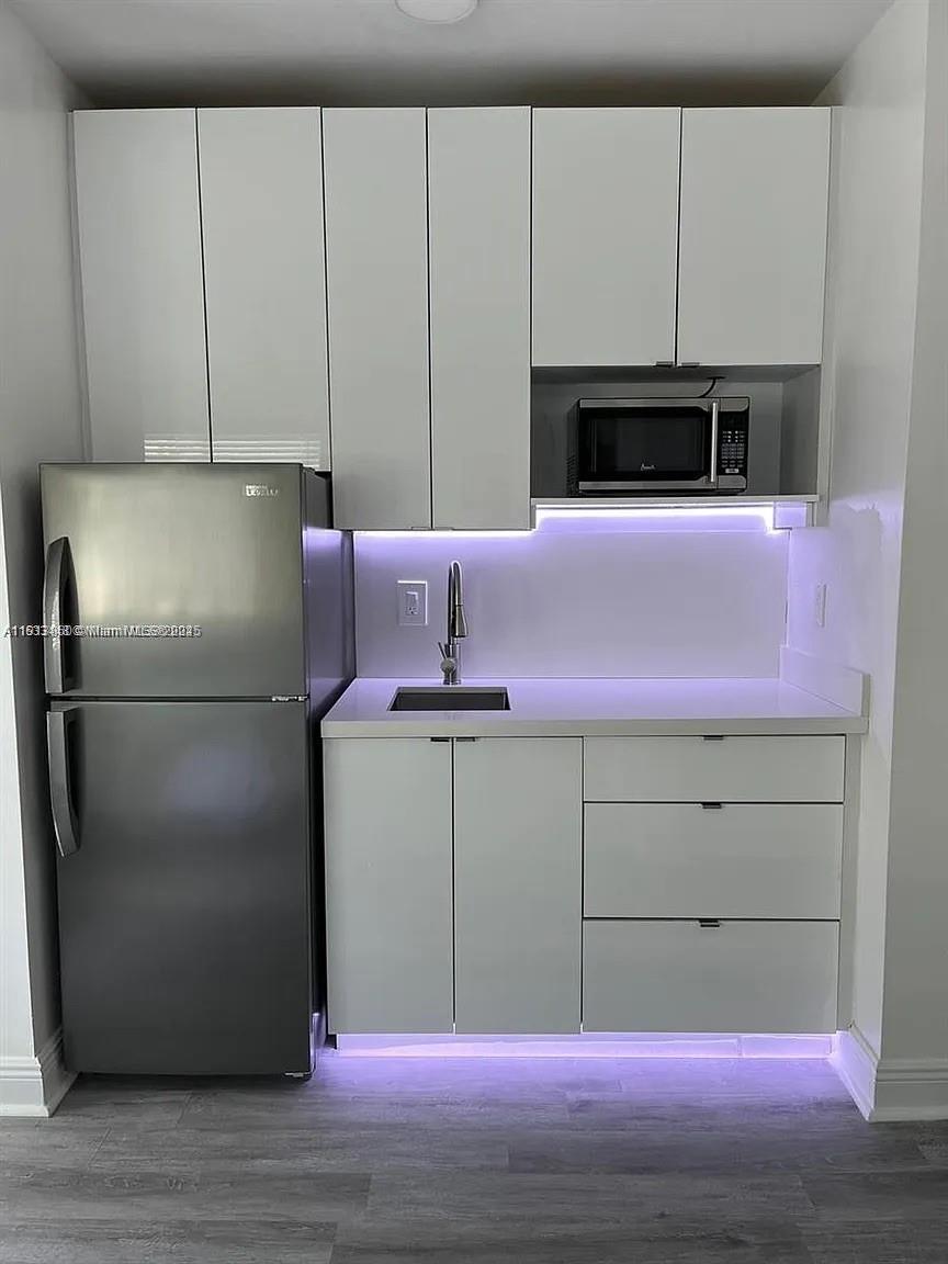 7325 Carlyle Avenue, Unit 12A Miami Beach, FL 33141 - Photo 2 of 7 a kitchen with cabinets and white stainless steel appliances