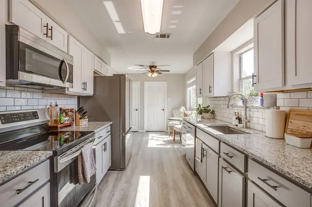 a kitchen with stainless steel appliances granite countertop a sink stove microwave and refrigerator