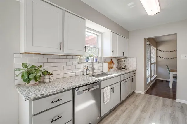 a kitchen with granite countertop stainless steel appliances a sink window and cabinets