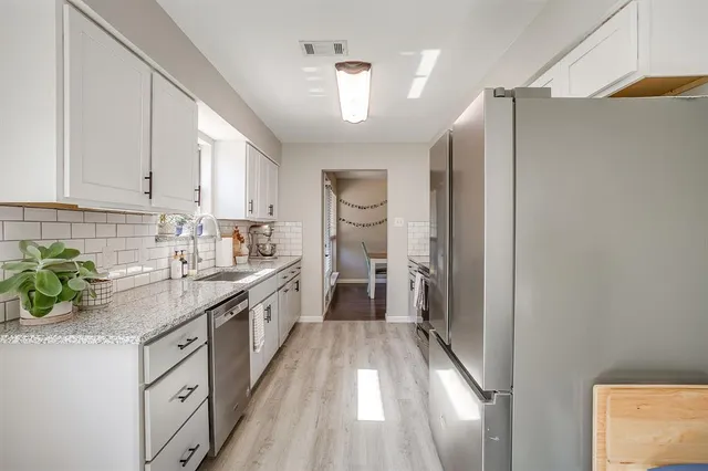 a kitchen with granite countertop stainless steel appliances and white cabinets