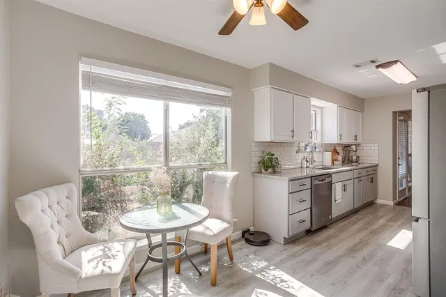 a kitchen with a dining table chairs and white cabinets