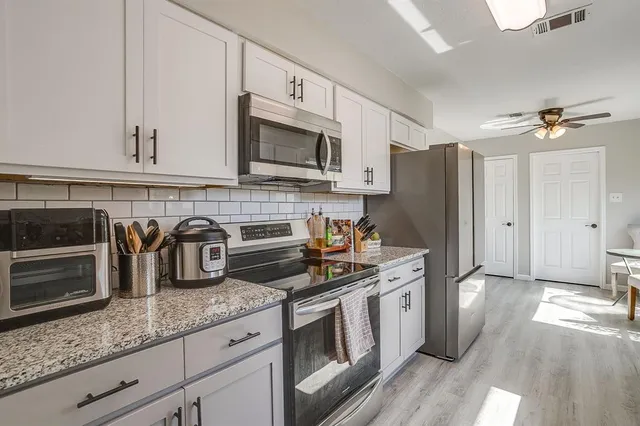 a kitchen with granite countertop a sink stove and refrigerator