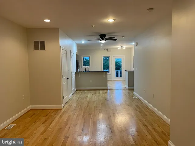 a view of a hallway with wooden floor and a kitchen