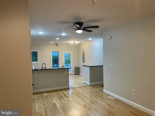 an empty room with wooden floor and a kitchen