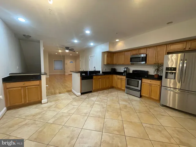 a kitchen with stainless steel appliances granite countertop a stove a sink a microwave a refrigerator and cabinets