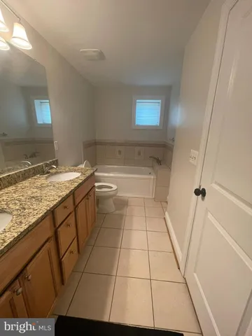 a bathroom with a granite countertop sink a toilet and a mirror