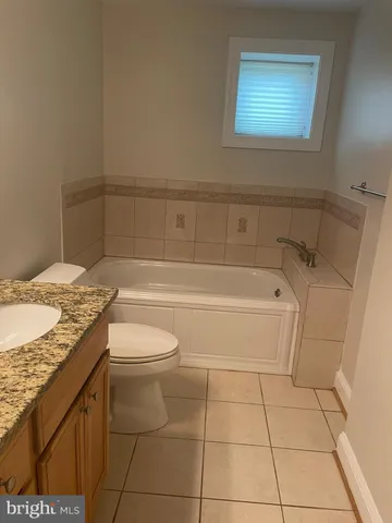 a bathroom with a granite countertop sink a toilet and bathtub