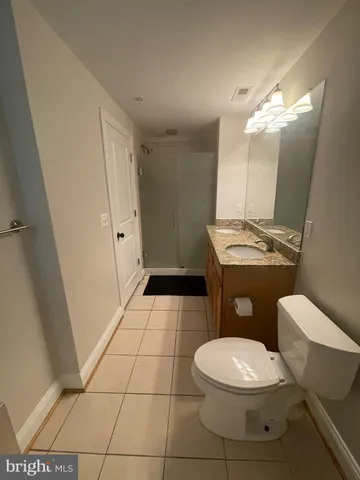 a white toilet sitting next to a bathroom sink and a mirror