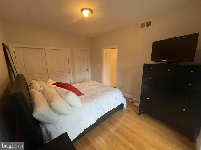 a bedroom with a bed and a flat tv screen on a dresser